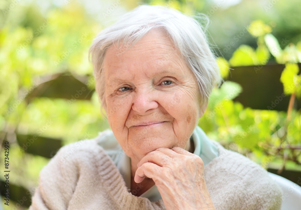 Senior woman smiling and dreaming in garden.