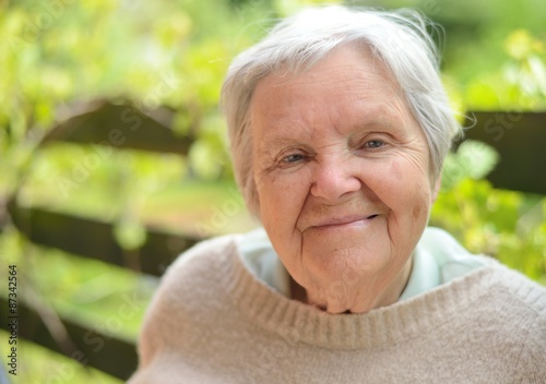 Senior woman smiling and dreaming in garden.