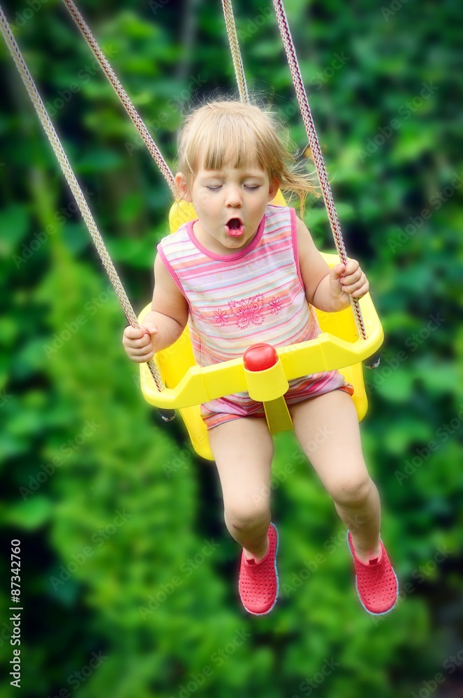 Cute little girl swings. Outdoors scenery.
