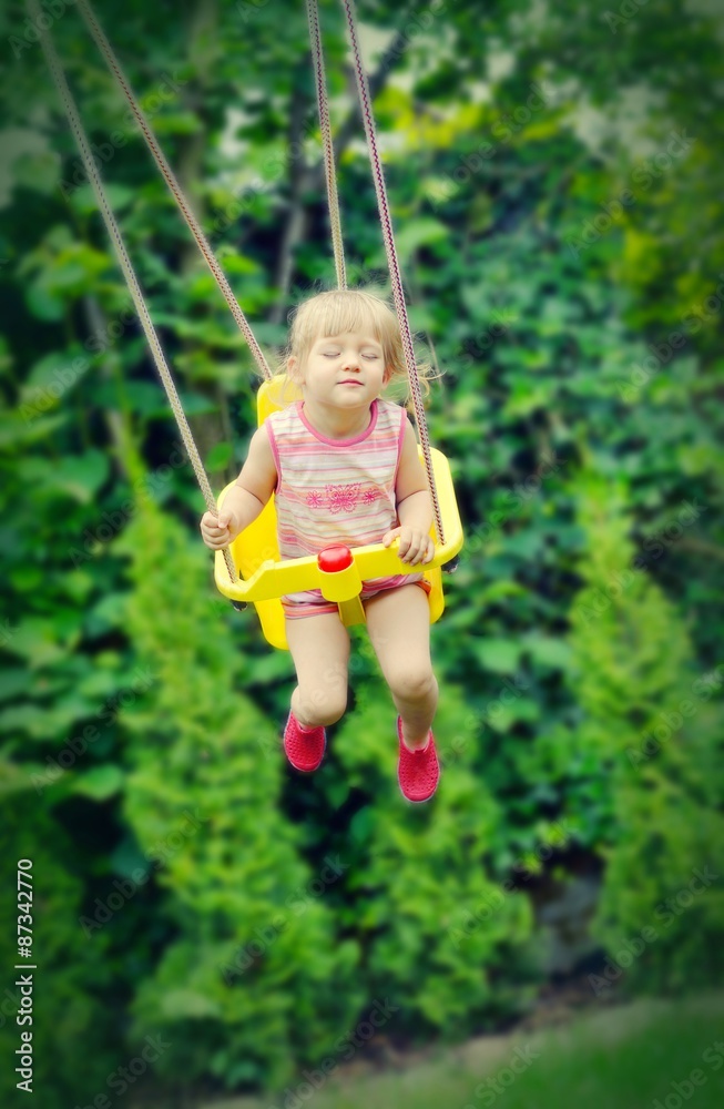 Cute little girl swings. Outdoors scenery.