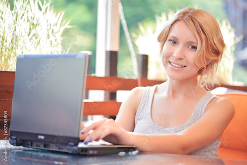 Smiling woman using laptop in cafe