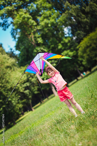 Little girl play with colored kite in the park.