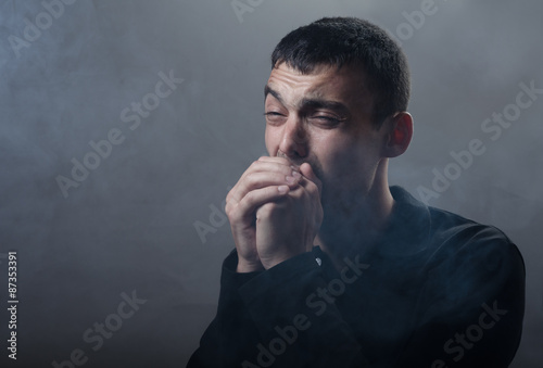 young man suffocating in the poisonous smoke