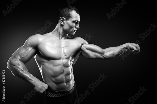 Strong and handsome young bodybuilder demonstrate his muscles an © Restyler