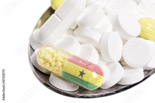 Spoon full of pills and a capsule with the flagdesign of Ghana.(