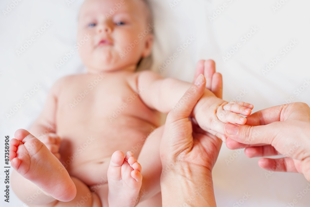 Mother makes finger massage for happy baby, apply oil on the hands, with white background