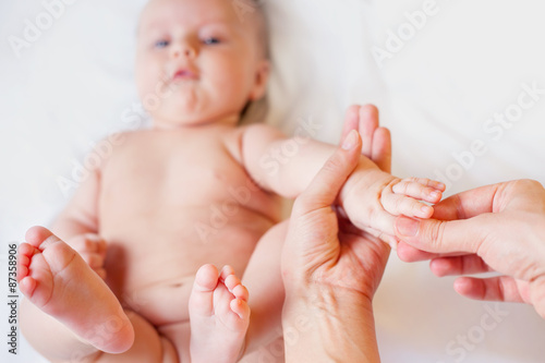 Mother makes finger massage for happy baby, apply oil on the hands, with white background
