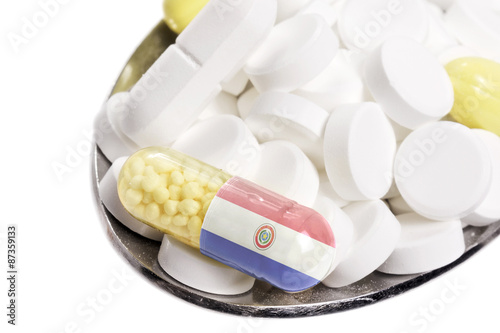 Spoon full of pills and a capsule with the flagdesign of Paragua photo