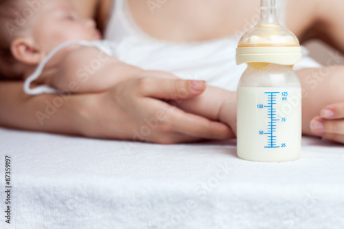 Mother holding a baby and bottle with breast milk