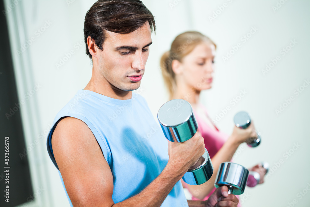 Couple exercising in gym, using weights Couple exercising in gym, using weights