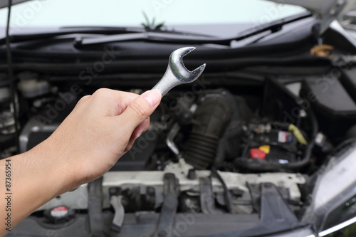 hand with wrench on car engine
