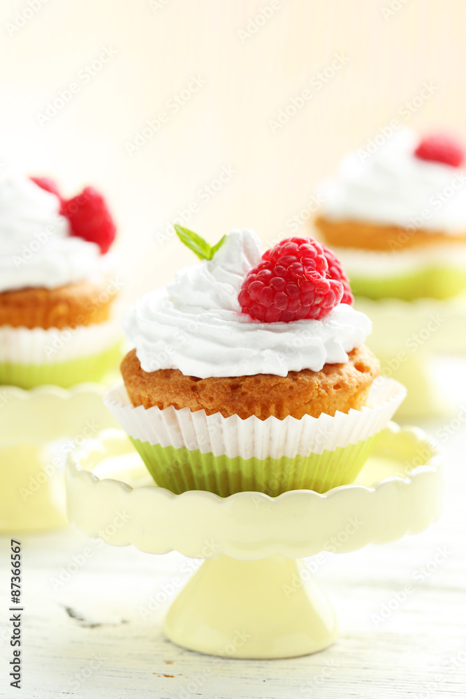 Raspberry cupcakes on cake stand on white wooden background
