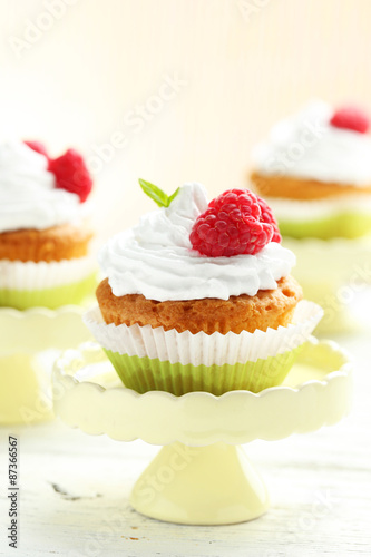 Raspberry cupcakes on cake stand on white wooden background