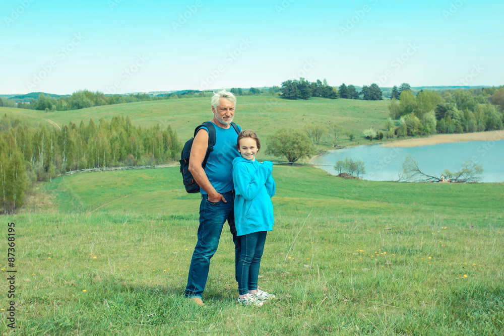 Portrait of grandfather and granddaughter in a landscape of open space Old man photographer on a camping trip with his granddaughter.