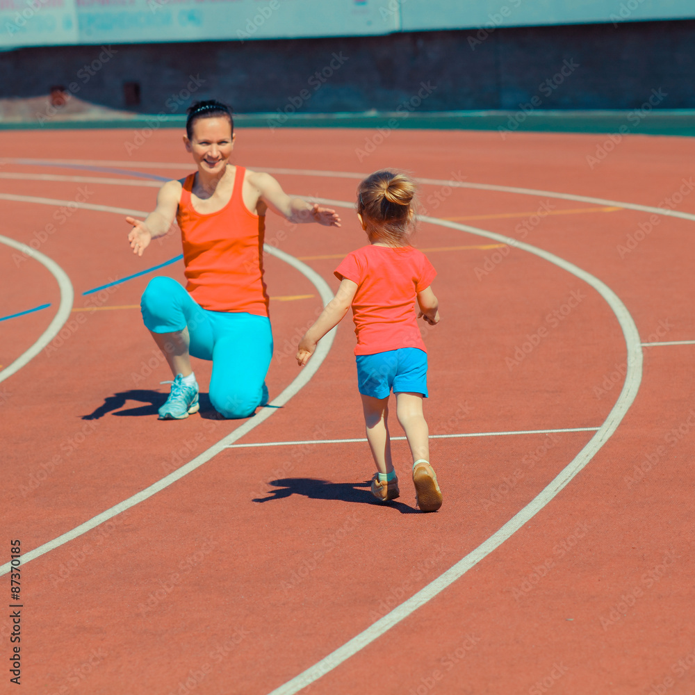 Obraz premium Mother & little daughter running around the stadium. Child runs away from mom at the stadium.
