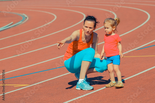 Mother & little daughter running around the stadium. Child runs away from mom at the stadium.