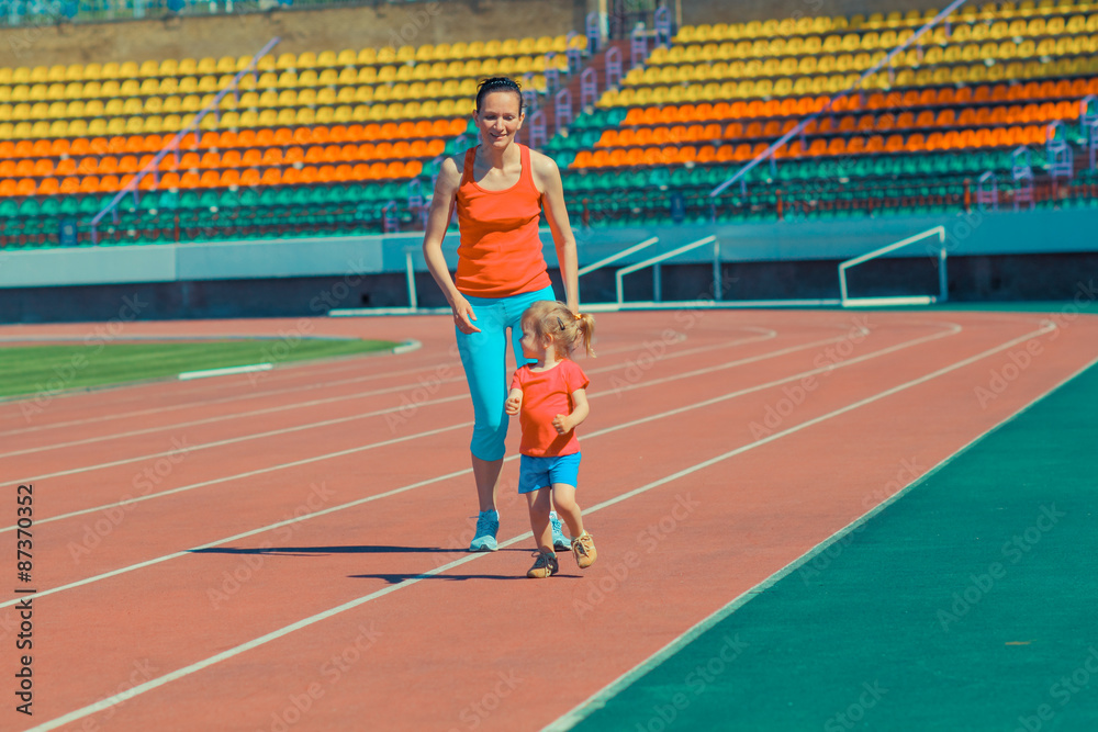 Mother & little daughter running around the stadium. Child runs away from mom at the stadium. Mother & little daughter running around the stadium. Child runs away from mom at the stadium.