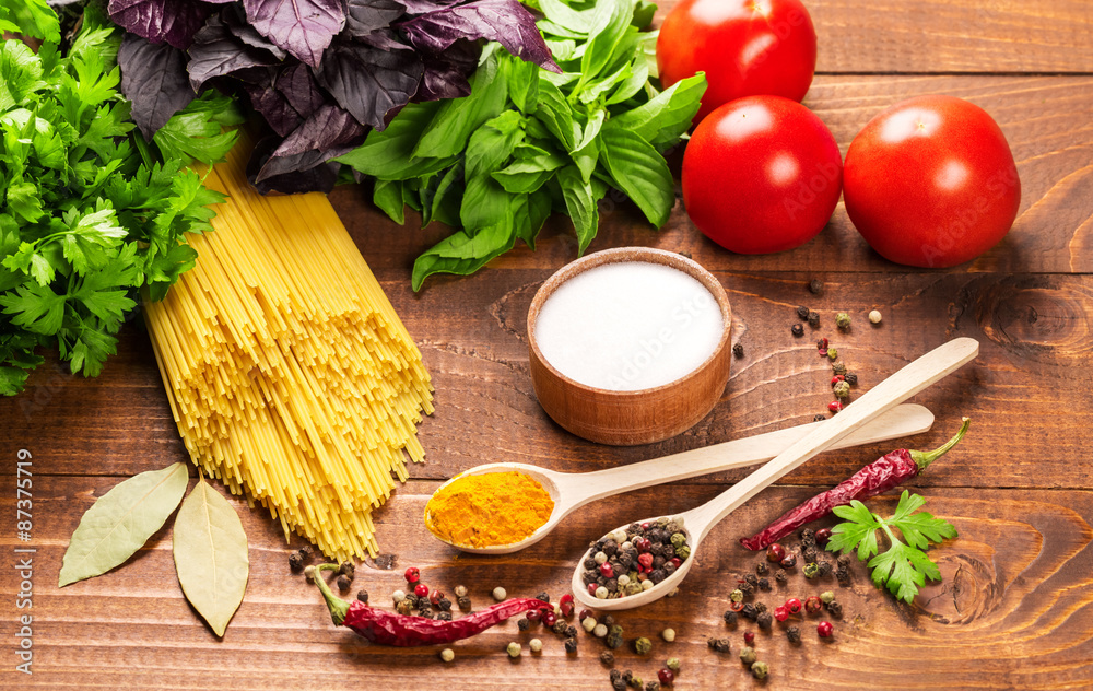 Raw pasta, vegetables, basil and spices on the wood table Raw pasta, vegetables, basil and spices on the wood table