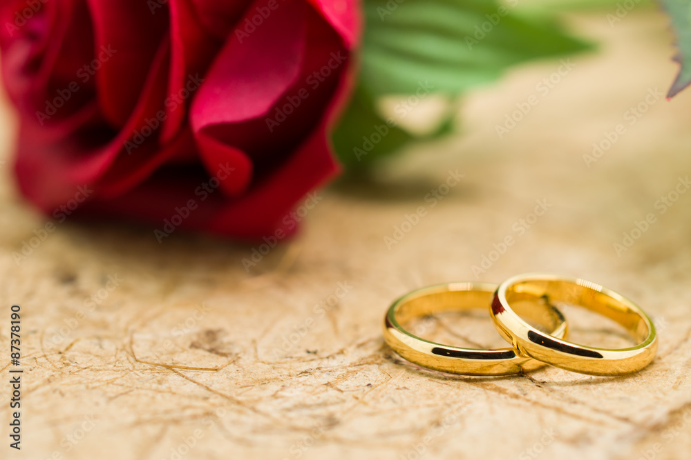 Wedding rings and artificial rose on brown background Wedding rings and artificial rose on brown background