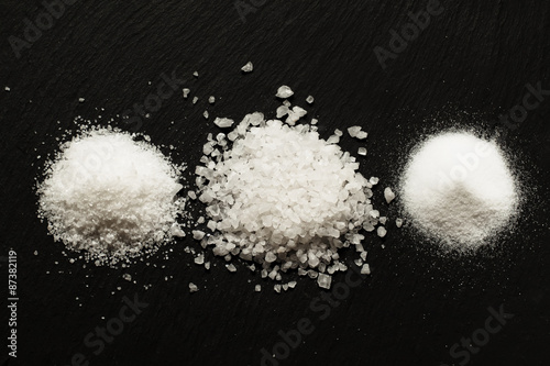 Tableau sur toile Three types of salt on dark stone background, selective focus