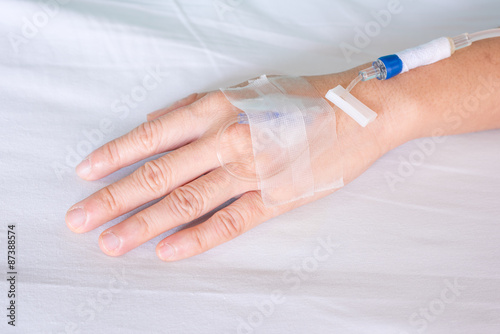 Hand of woman with drip in hospital bed
