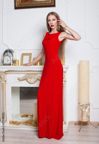 Beautiful brunette woman in a red dress. Studio shot. Long hair. Red lips.