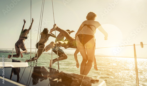 group of friends jumping in the water from the boat