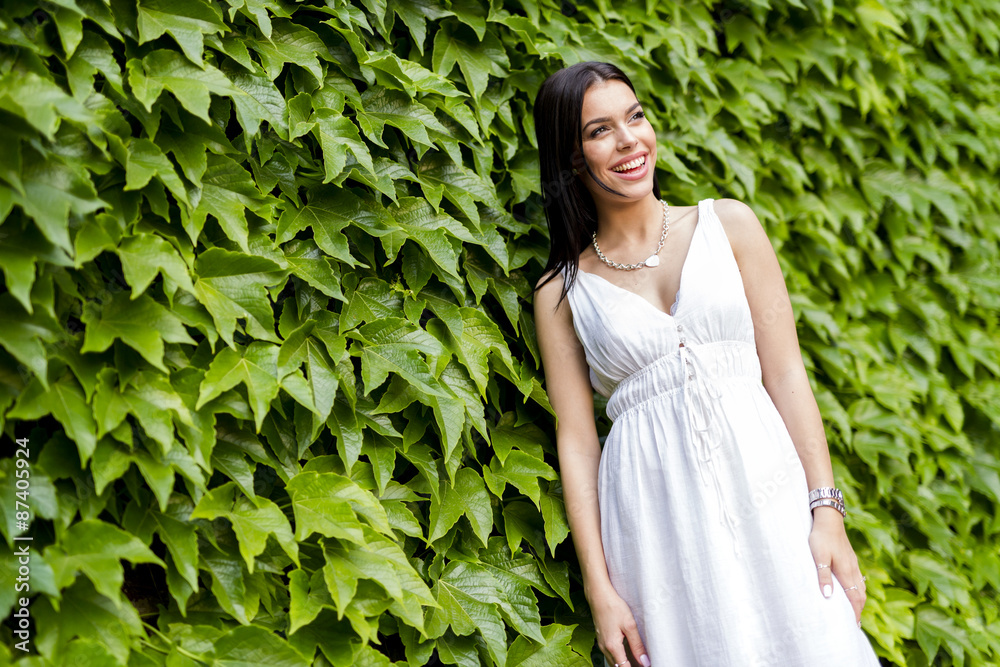 Beautiful young woman posing with green leaves in the background Beautiful young woman posing with green leaves in the background