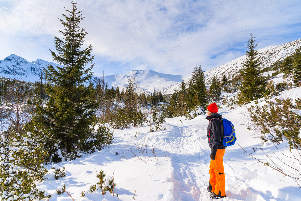 Young woman backpacker tourist on hiking trail in winter landscape of Gasienicowa valley, Tatra Mountains, Poland