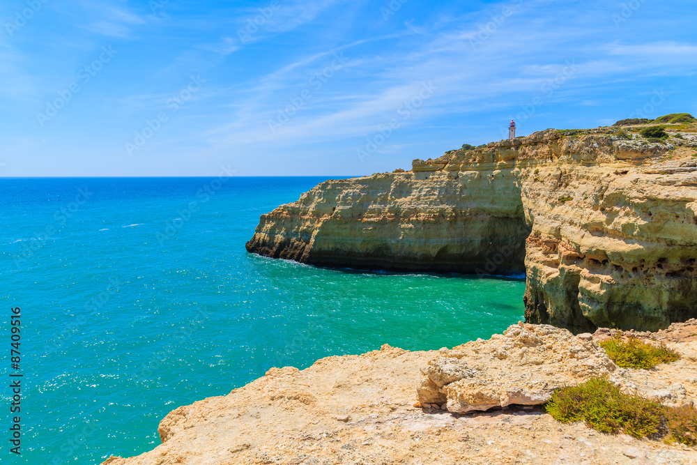 Lighthouse building on top of cliff on coast of Portugal near Carvoeiro town, Algarve region