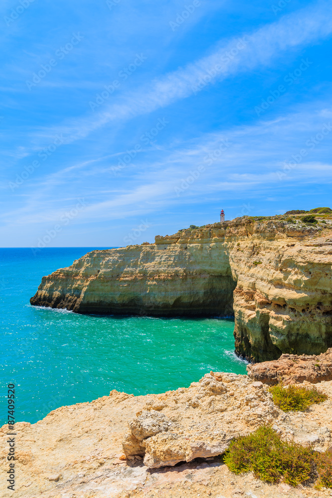 Lighthouse building on top of cliff on coast of Portugal near Carvoeiro town, Algarve region