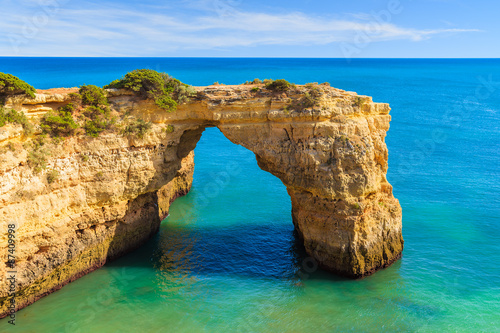 Rock cliff arch near Marinha beach and blue sea on coast of Portugal in Algarve region