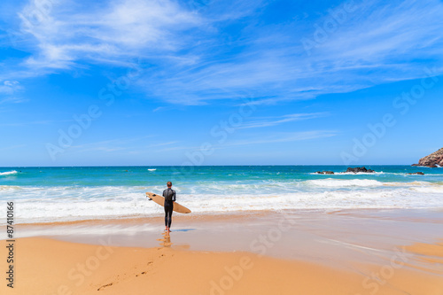Surfer on Praia do Amado beach on sunny summer day, Algarve region, Portugal