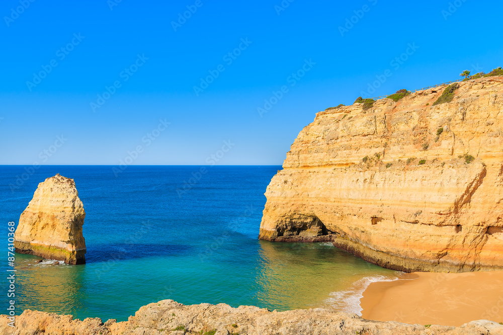 Fototapeta premium View of sandy beach and rock cliffs near Carvoeiro town, Algarve, Portugal