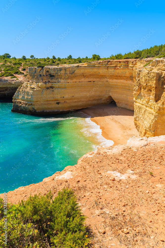 Sandy beach with cliff rocks in small cove near Carvoeiro town, Algarve region, Portugal