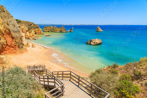 Wooden walkway to famous Praia Dona Ana beach with turquoise sea water and cliffs, Portugal photo