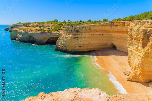 View of beach with golden color cliff rocks near Carvoeiro town, Algarve region, Portugal