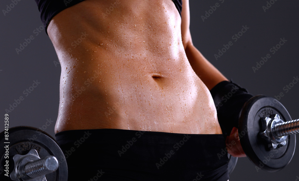 Athletic woman pumping up muscules with dumbbells Athletic woman pumping up muscules with dumbbells