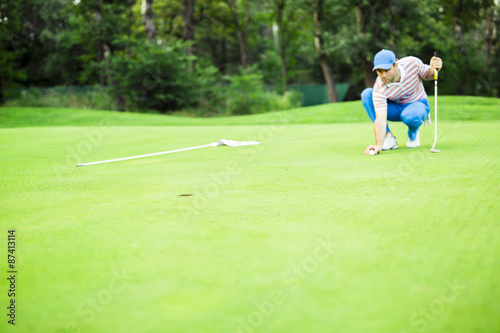 Golf player marking ball on the putting green
