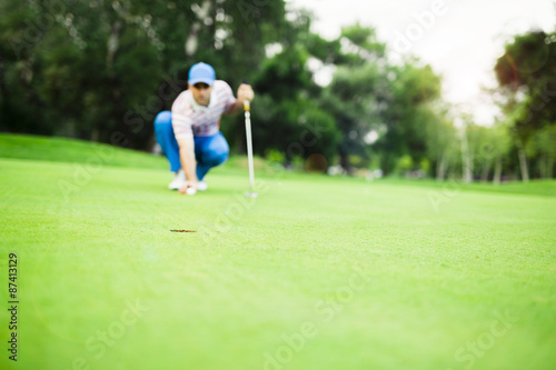 Golf player marking ball on the putting green