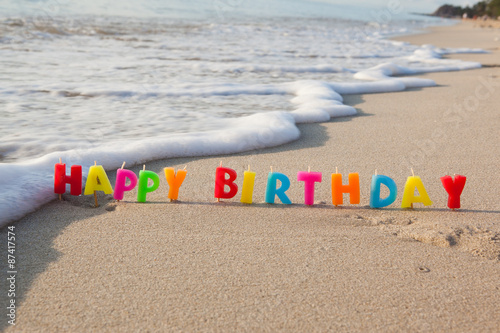 Happy birthday candles on a beach.