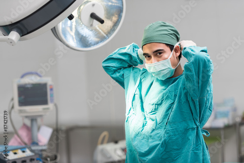 Male surgeon tying mask at operating room photo