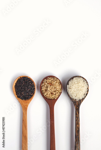 Brown, white and black rice in wooden spoon 