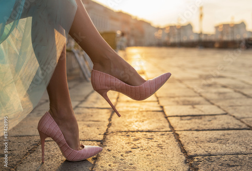 Leinwand Poster Frau in Schuhen mit hohen Absätzen in der Stadt von Sonnenaufgang