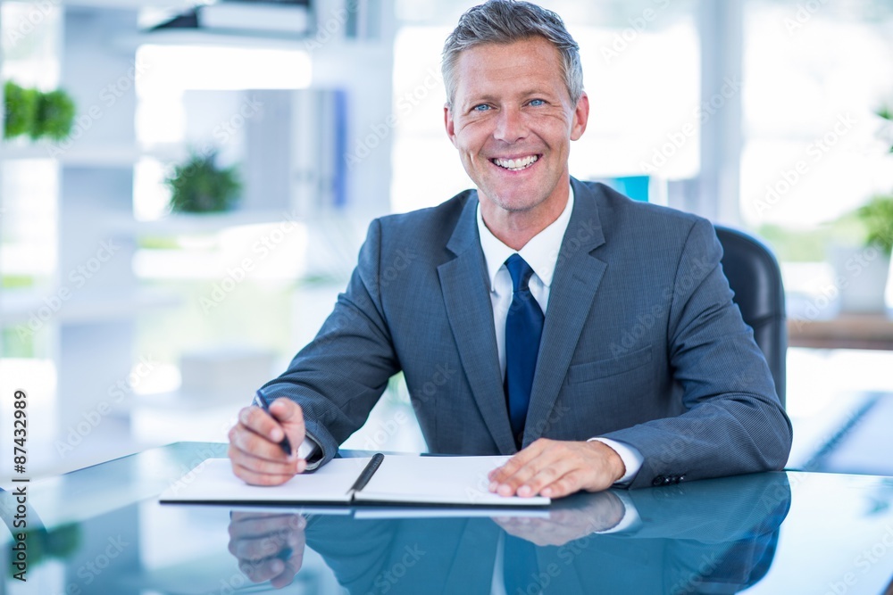 Businessman writing on clipboard and looking at camera Businessman writing on clipboard and looking at camera
