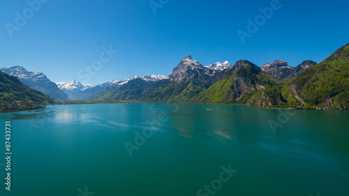 Panorama of Swiss Alps, peaks covered with snow. Lake Uri in central Switzerland. Gorgeous summer day and clean bright blue sky