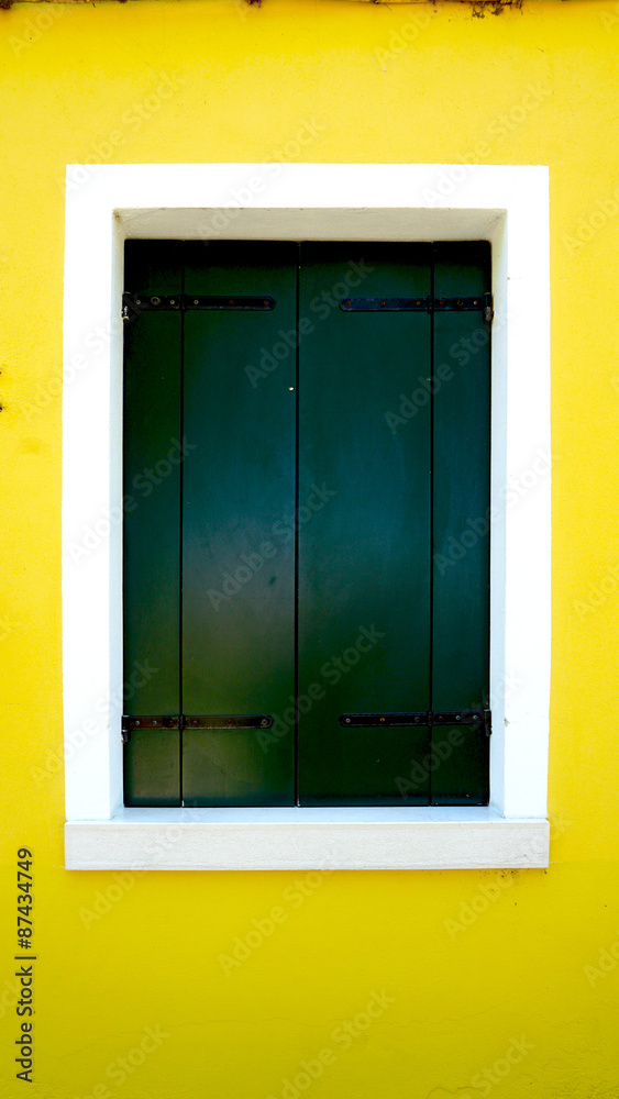 green wood paint Window in Burano with bright yellow wall