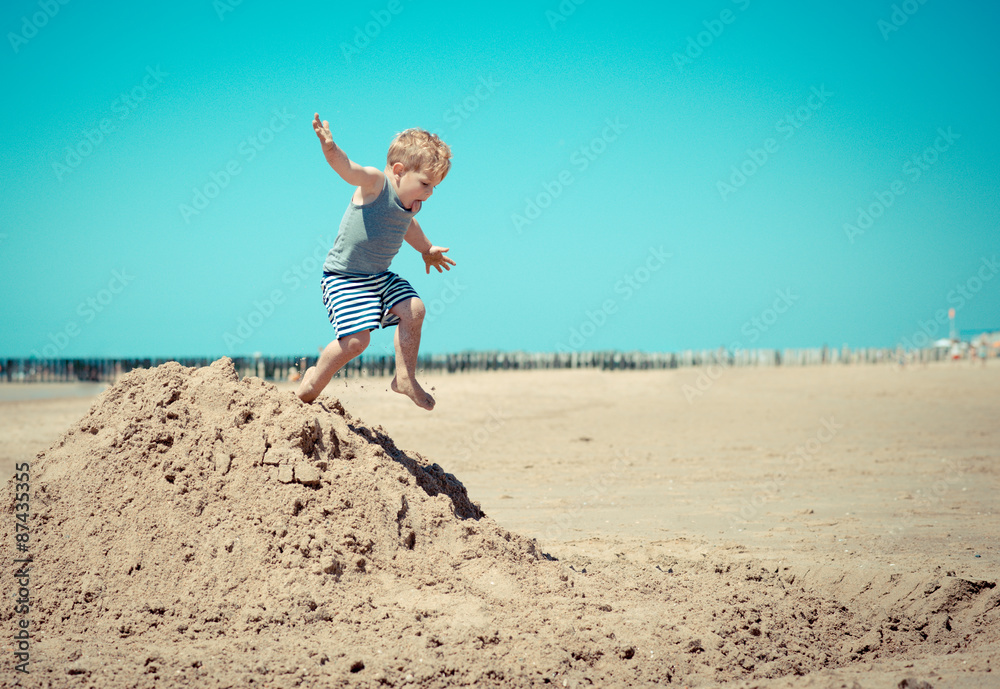 Little boy child jumps from a mountain on the beach Little boy child jumps from a mountain on the beach