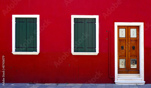 wooden door and two windows on red wall