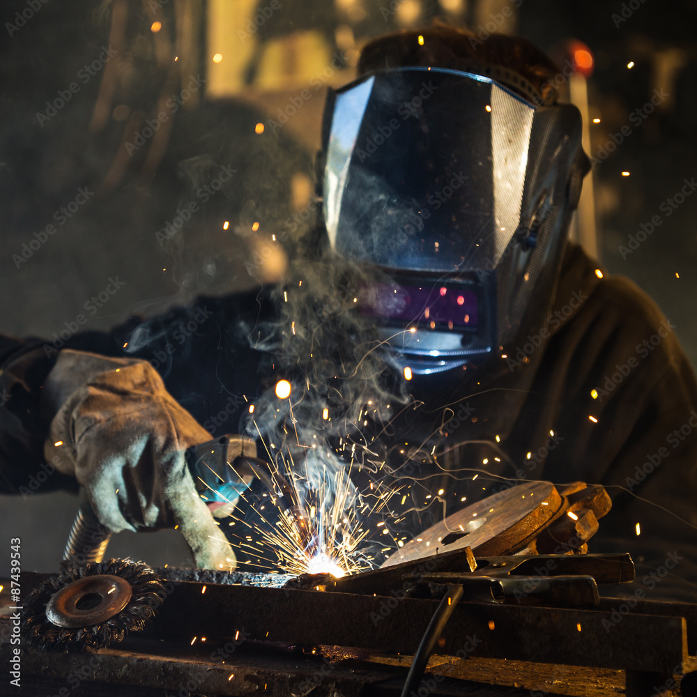 Welder in action with bright sparks. Construction and manufacturing theme. - obrazy, fototapety, plakaty 